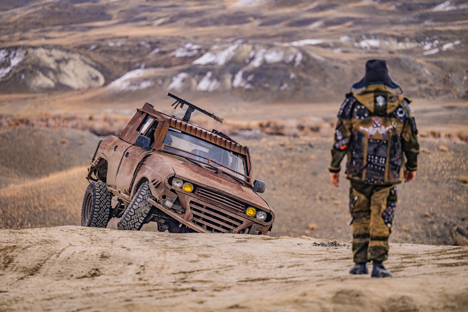 Alexey Gubarev in post-apocalyptic gear next to a MadWay Rally armored truck in the mountains