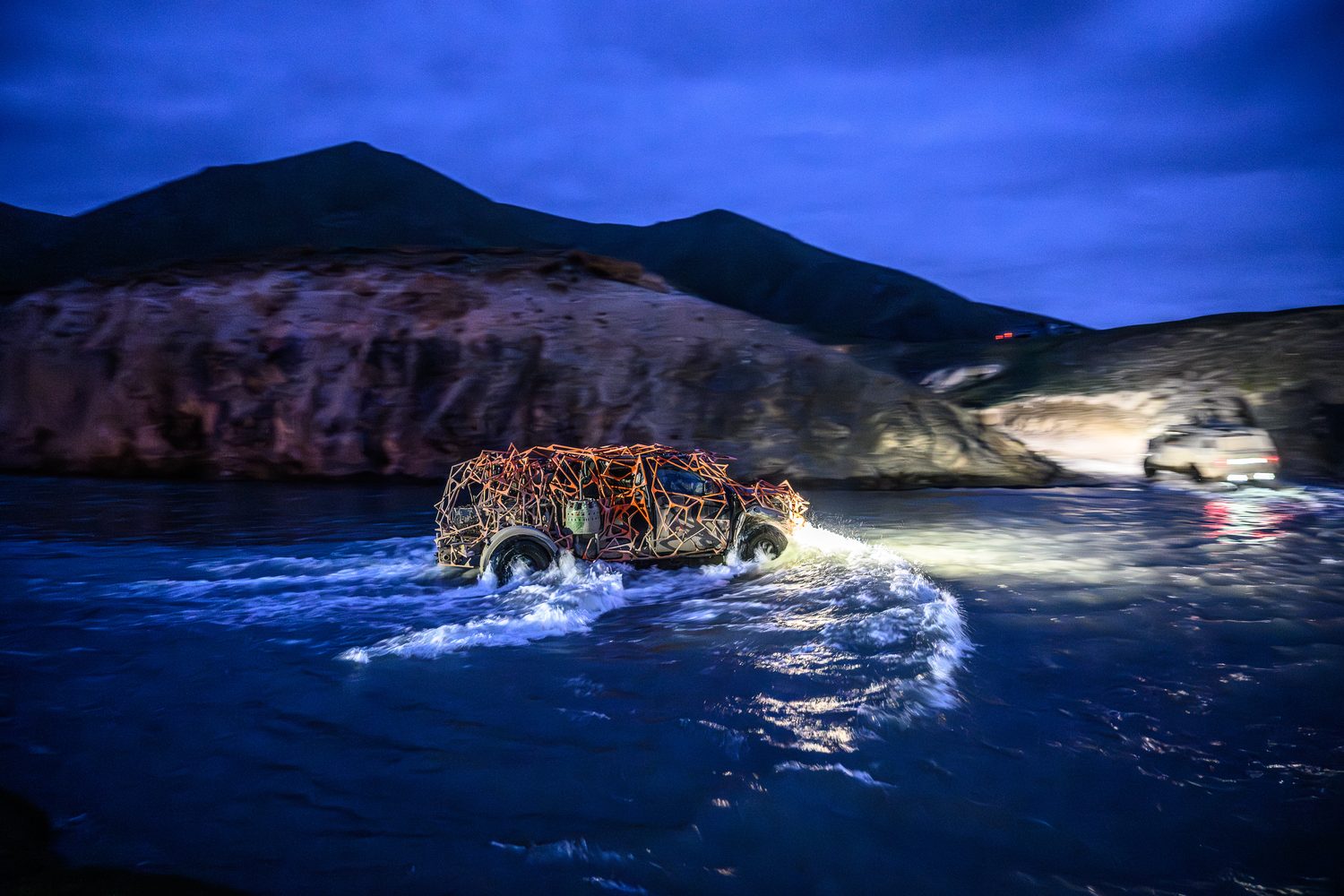 MadWay Rally car crossing a river at night in China with headlights blazing