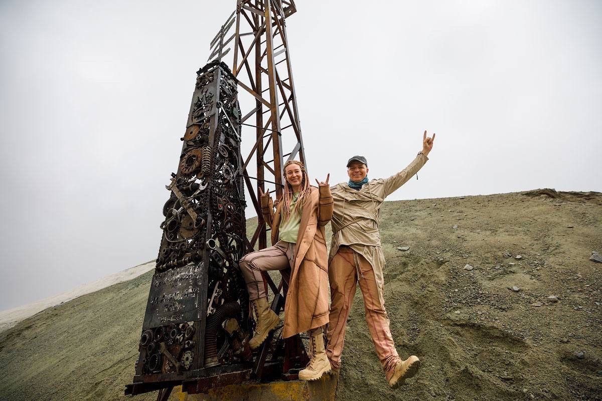 Alexey Gubarev and Anna Gubareva at the roadside sculpture made of car and motorcycle parts, Kyrgyzstan